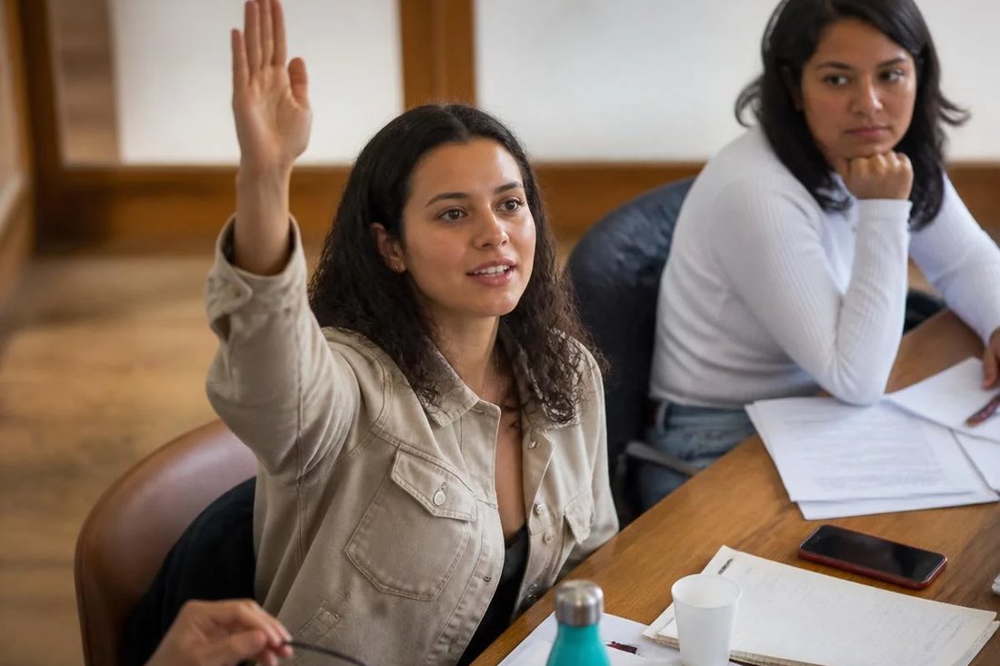 Facilitador de pé apontando para um argumento escrito no quadro durante a sessão